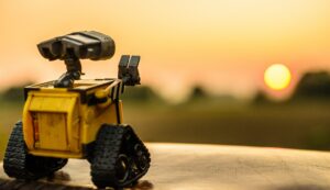 A WALL-E robot toy waves to the setting sun.