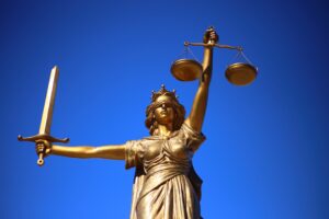 Justice holds her scales and sword aloft with a blue background.