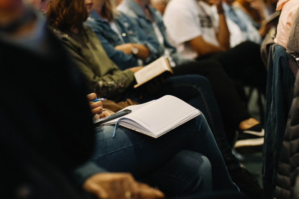People meeting with an open notebook on someone's lap in the center of the image.